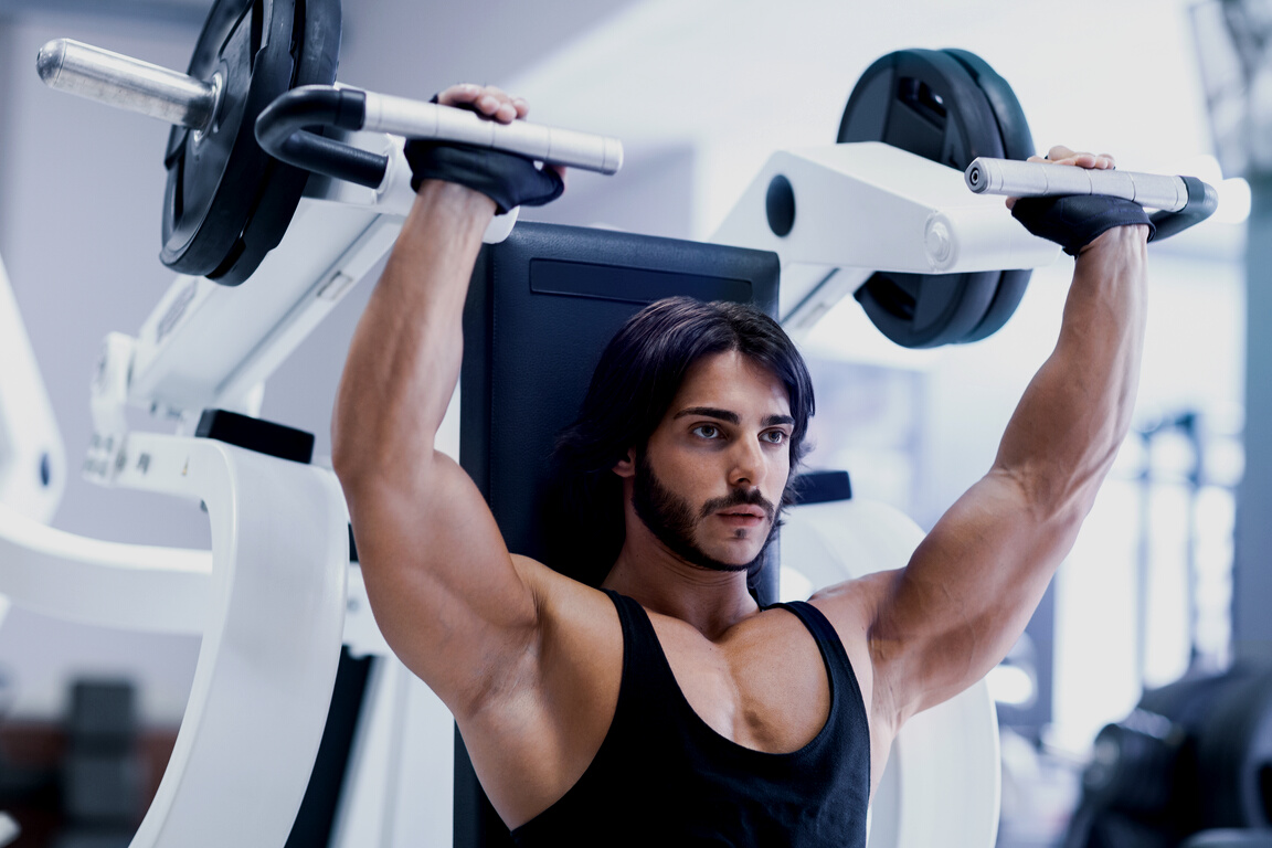 Bodybuilder working out with shoulder press machine
